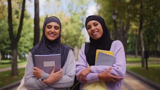 Portrait of muslim women with books outdoors, students lifestyle, education