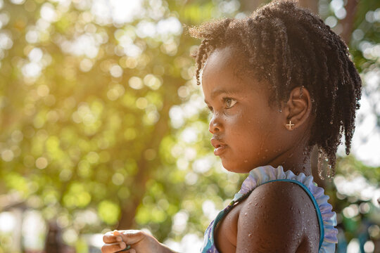 Retrato horizontal de cerca de una hermosa ni&ntilde;a afroamericana de cabello afro de perfil en un hermoso d&iacute;a de verano al aire libre.