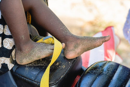 Imagen horizontal de cerca de los pies sucios de un pequeño niño afroamericano desconocido cubiertos de mucha arena. 