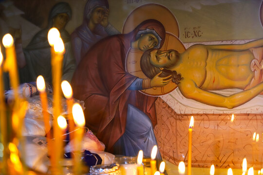 Memory of the dead. Candles burn on the memorial candlestick in the Orthodox church against the backdrop of a fresco with the Mother of God and Christ. Sacrificial bread on the table. 