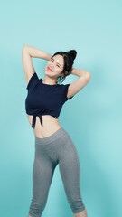 Obraz premium Fitness sportswear woman smile and pose body exercise at camera isolated on blue green background. Perfect body sporty woman relaxing after training. Fit and firm people. Sport Health and wellness.