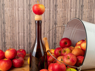 Apple cider vinegar in a bottle with apples on a wooden background.