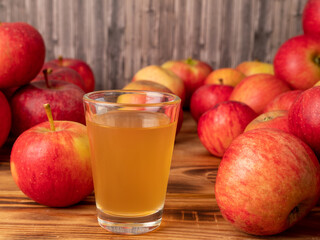 Apple cider vinegar in a glass with apples on a wooden background.