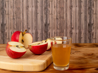 Apple cider vinegar in a glass with apples on a wooden background.