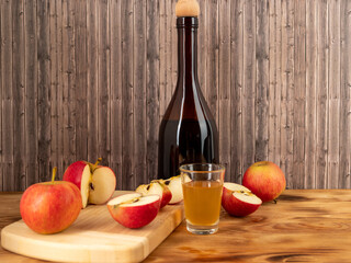 Apple cider vinegar in a bottle with apples on a wooden background.