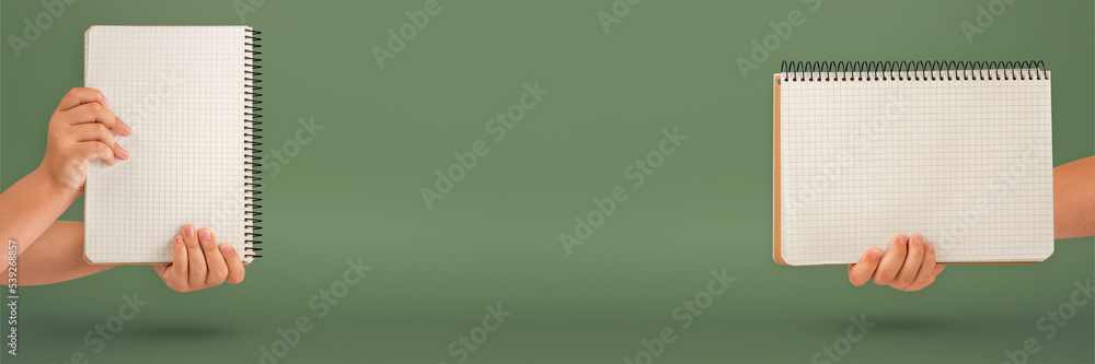 Wall mural notepad in hand. blank notepad in the hands on a green background. hands hold a book without text. t