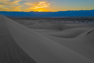 Sand dunes at sunset. Mesquite Flat Sand Dunes and abstract geometry of curving silhouette desert hills at sunset in Death Valley National Park, California