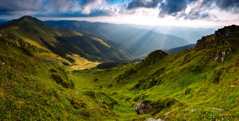 Amazing landscape of mountain valley and Farcaul peak in sunlight. View of   dramatic sky, green hills and colorful clouds. Mountain Maramures Nature Park. East Carpathians. Romania. Europe.