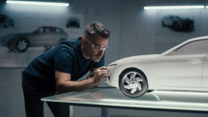 Senior automotive design engineer uses a rotary tool for perfecting the rake sculpture of a car...