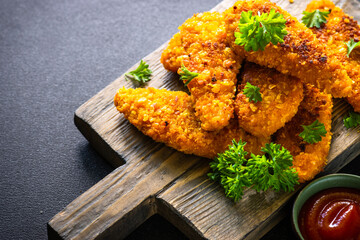 Chicken nuggets with ketchup sauce on serving board. American food.