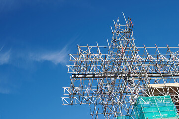 looking up at metal scaffolding at construction site with blue sky