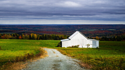 Fototapeta na wymiar A white barn in the Quebec fall colors