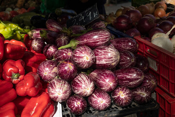 puesto de mercado de alimentos de los agricultores con variedad de verduras org&aacute;nicas. 
Un primer plano de berenjenas, acompa&ntilde;adas de pimientos y cebollas.