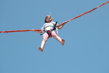 Little girl bouncing high in the air using a bungee trampoline