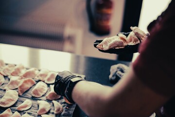 Closeup of chef hands preparing dumplings to put in the oven