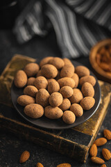 Almonds in chocolate coated in cocoa on plate.