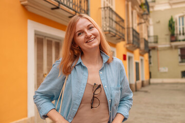 Stylish happy young woman standing in an urban street laughing at the camera with copy space 