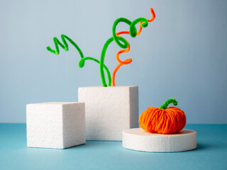 Funny string and wire pumpkins on podiums of rectangular shapes on a blue background.