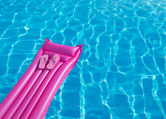 Beach summer holiday background. Inflatable air mattress, flip flops on swimming pool.