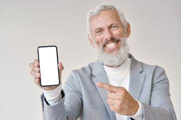 Happy older senior business man wearing suit holding smartphone pointing at white mock up screen...