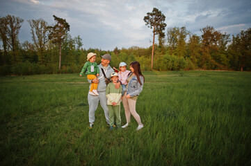 Parents with three kids having fun together at meadow.