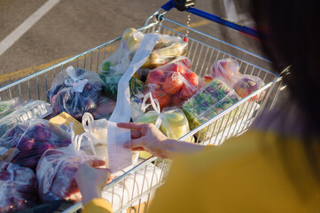 Woman checks paper check after shopping for groceries at mall by checking Dear Amount bill in a...