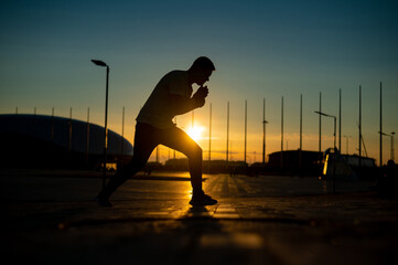 A man trains boxing at sunset outdoors.