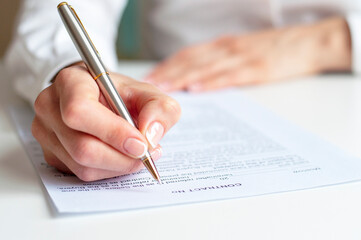 Close shot of a woman hand writing something on the paper on the foreground