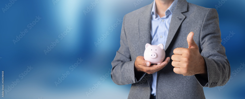 Wall mural Man holding a piggy bank in his hand