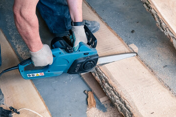 Chainsaw in action cutting wood. Man cutting wood with a saw, dust and movements. A man saws a...