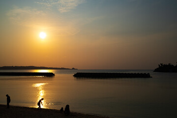 Fototapeta na wymiar 沖縄の夕陽と海、人のシルエット