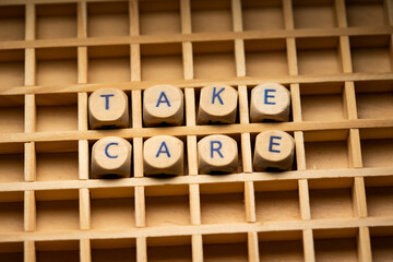 Take Care. Wooden dice arranged in a box, to the words Take Care. Helping hand, advice and motivation.