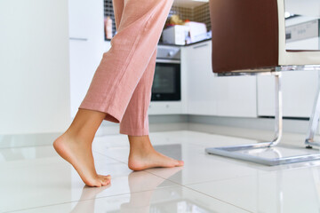 Female barefoot legs on heated warm floor at home kitchen - Powered by Adobe