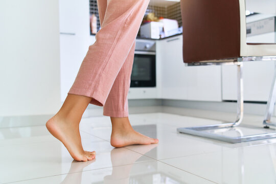Female barefoot legs on heated warm floor at home kitchen