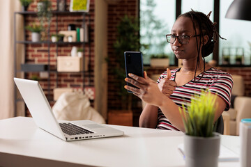 Freelancer showing appreciation gesture on smartphone videocall, woman working from home. Employee...