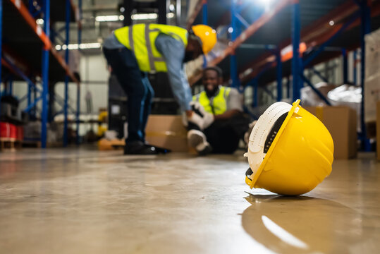 Factory Accident, Industrial accident. Warehouse staff having accident in the factory, industrial worker injured during working having pain on leg, worker helping and giving the injured first aid