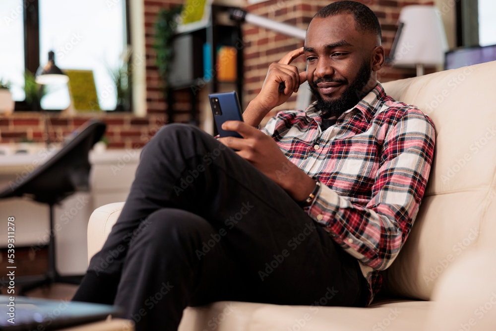 Poster male freelancer browsing internet on smartphone and texting messages, looking at social media websit