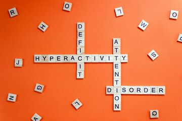 Words Attention Deficit Hyperactivity Disorder on wooden blocks with the letters on orange background. Minimal concept of ADHD.