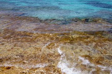 Rocky beach with a turquoise blue sea and waves in spain