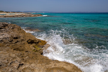 Rocky beach with a turquoise blue sea and waves in spain