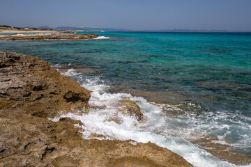 Rocky beach with a turquoise blue sea and waves in spain