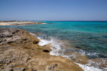 Rocky beach with a turquoise blue sea and waves in spain