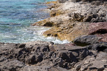 Rocky beach with a turquoise blue sea and waves in spain