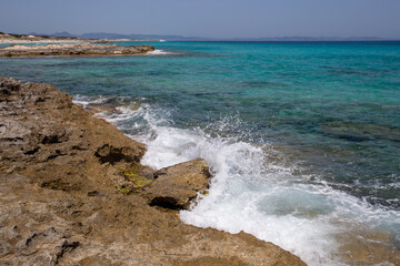 Rocky beach with a turquoise blue sea and waves in spain