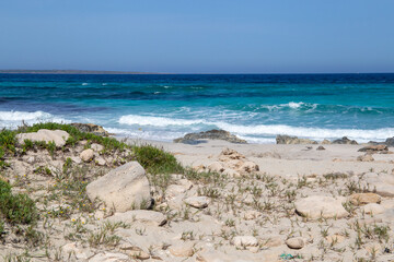 Rocky beach with a turquoise blue sea and waves in spain