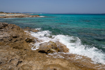 Rocky beach with a turquoise blue sea and waves in spain