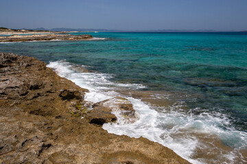 Rocky beach with a turquoise blue sea and waves in spain