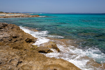 Rocky beach with a turquoise blue sea and waves in spain