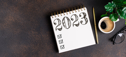 New year resolutions 2023 on desk. 2023 resolutions list with notebook, coffee cup on table. Goals, resolutions, plan, action, checklist concept. New Year 2023 template, copy space