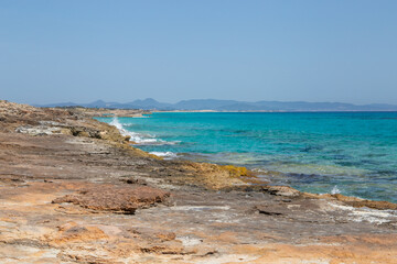 Rocky beach with a turquoise blue sea and waves in spain